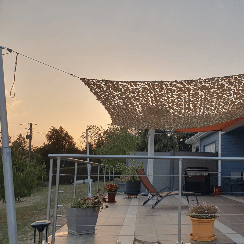 Rete mimetica beige tesa con corda a cricchetto sopra una terrazza al tramonto