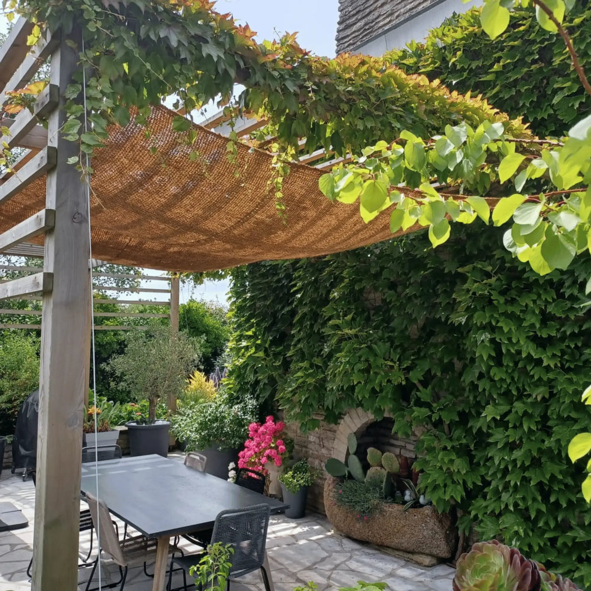 Telo ombreggiante in cocco sopra un tavolo da giardino con rampicante