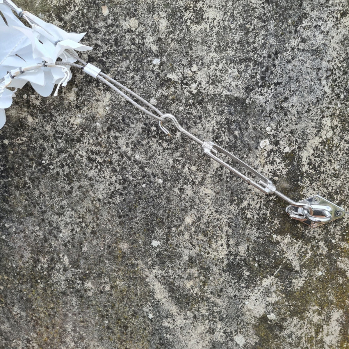 Tenditore e gancio di fissaggio su un muro in pietra con angolo di rete mimetica bianca
