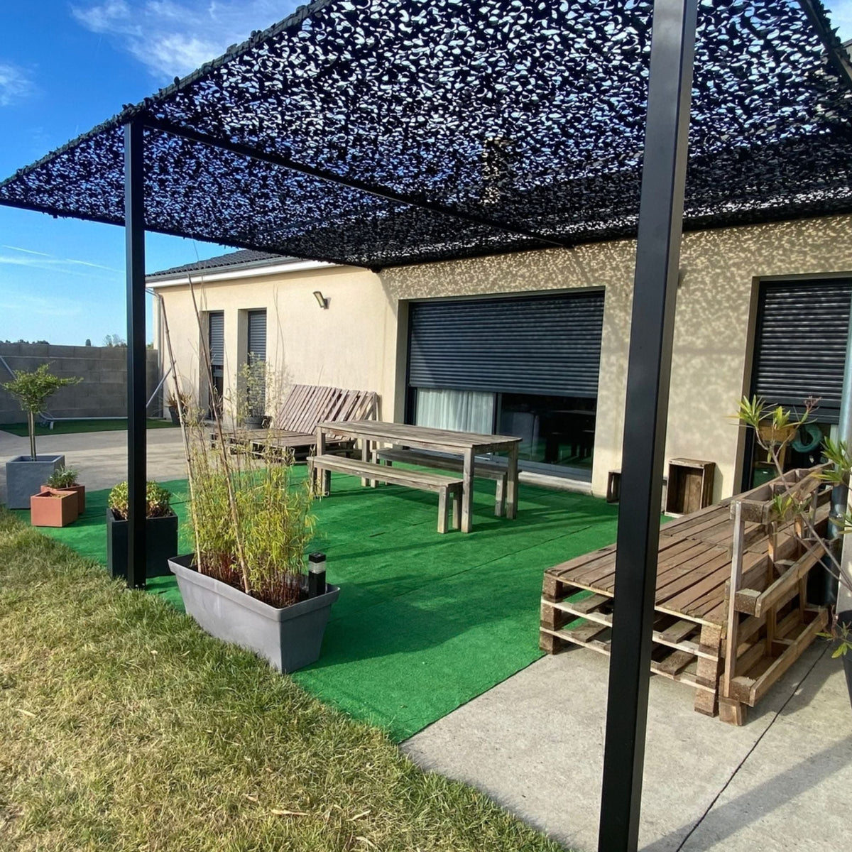 Rete mimetica nera sopra una pergola in una terrazza con prato