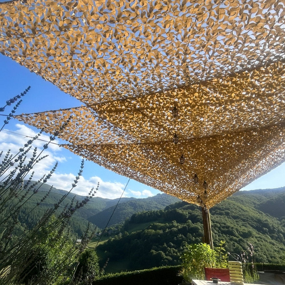 Reti mimetiche triangolari beige sopra una terrazza con vista sulle montagne