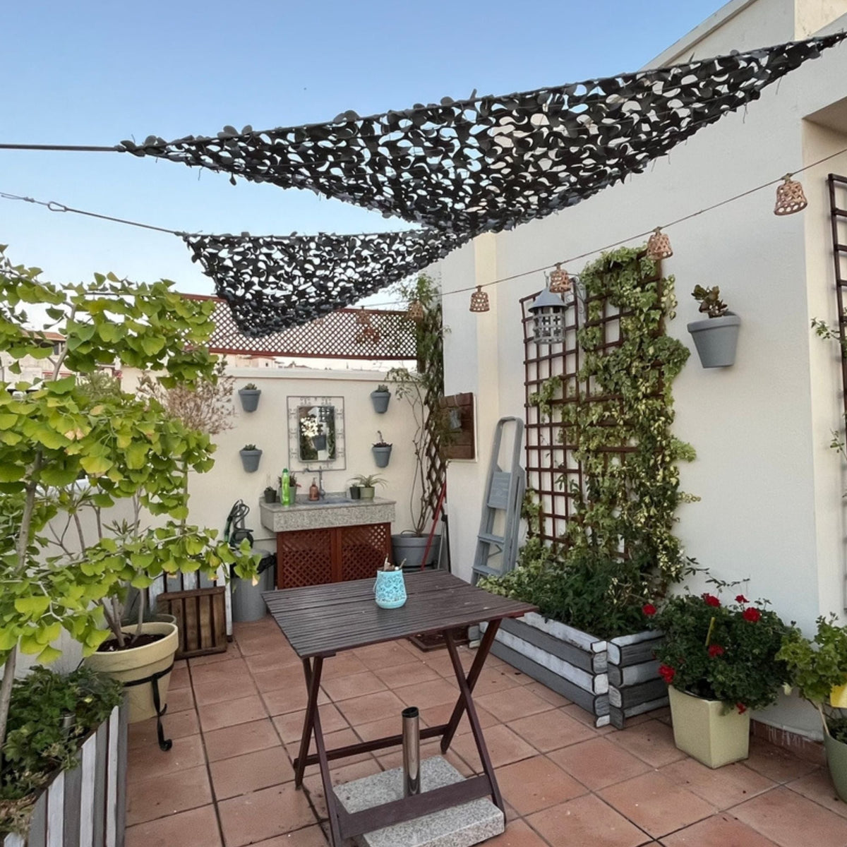 Reti mimetiche triangolari scure sopra una terrazza con tavolo