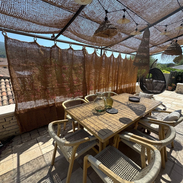 Tenda in fibra di cocco appesa in una terrazza con tavolo da pranzo
